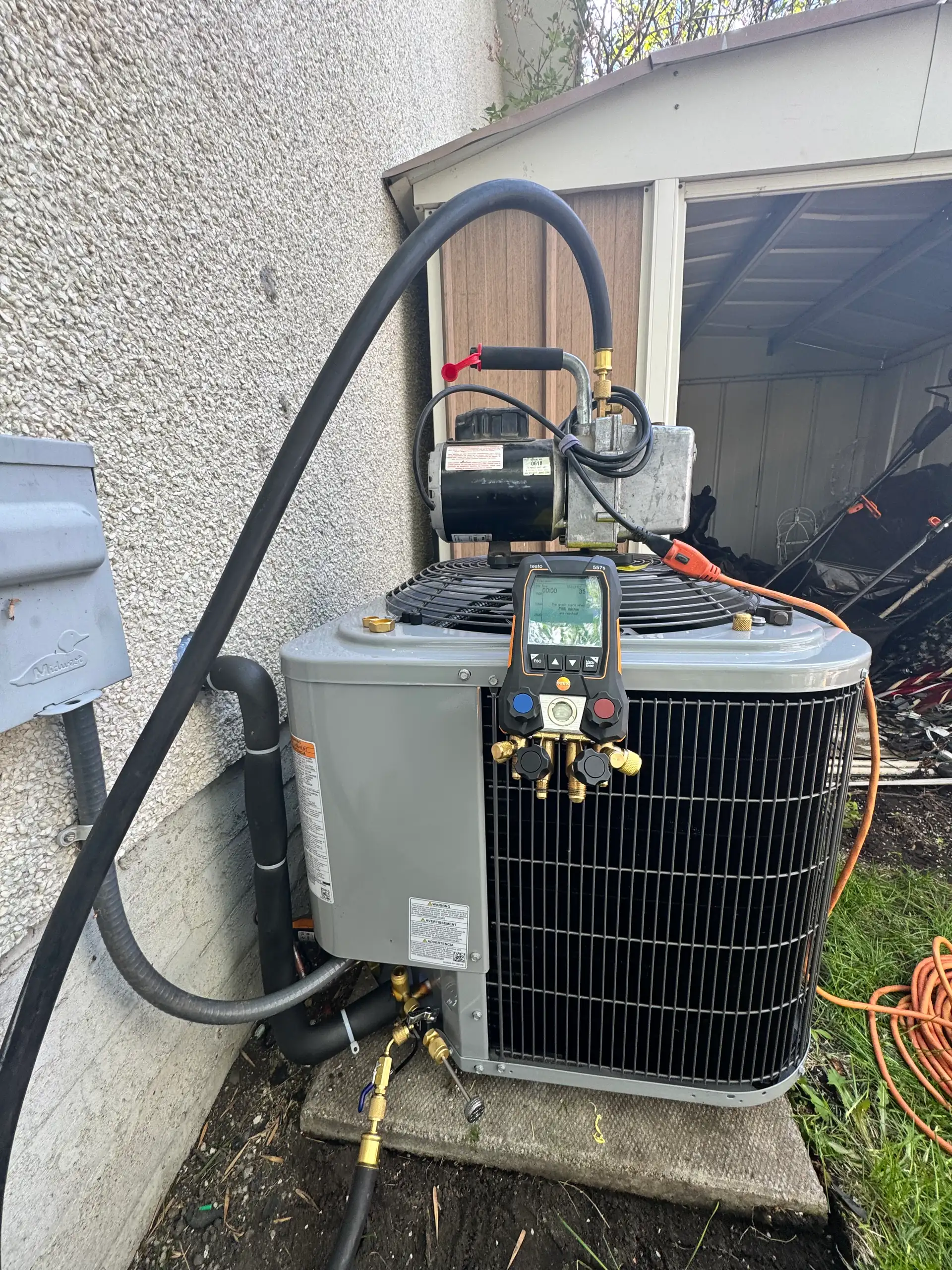 Digital gauges and vacuum pump connected to a central AC condenser during service in Calgary