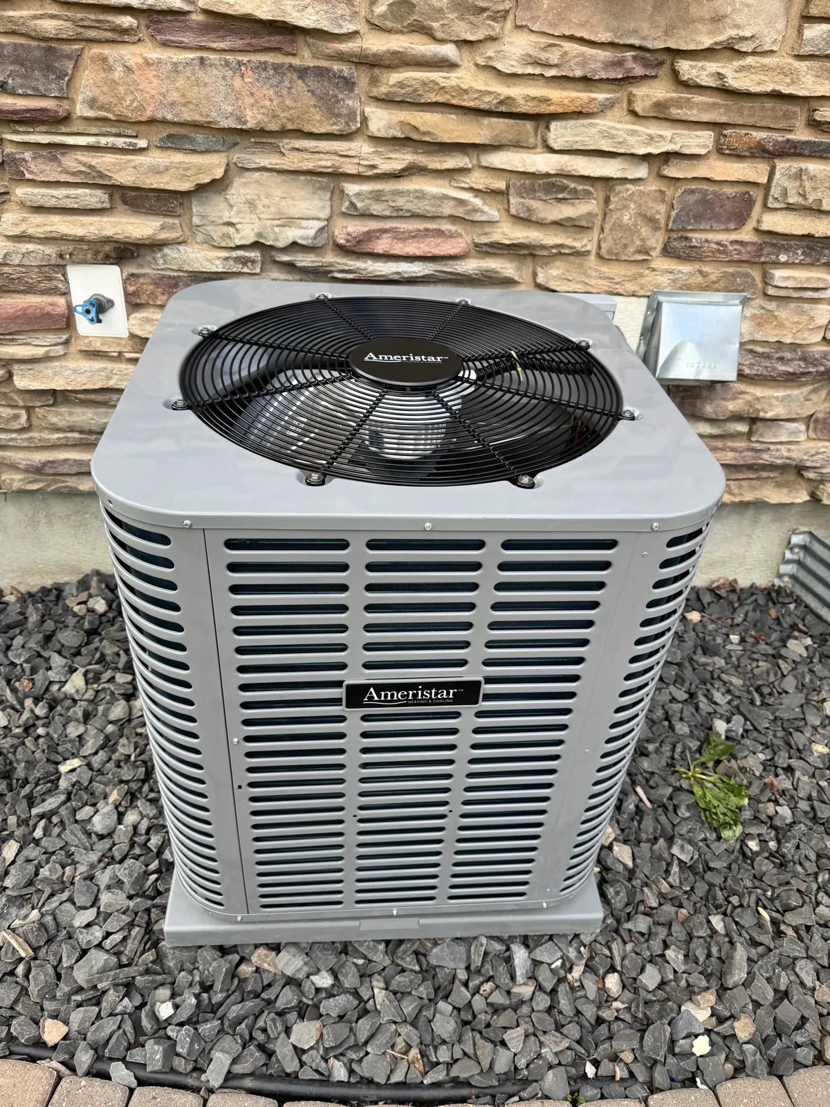 HVAC technician performing spring AC tune-up on outdoor condenser at a Calgary home